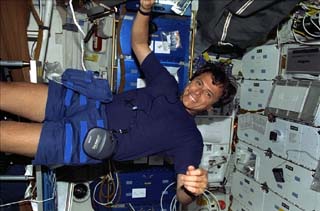 Mission specialist Franklin Chang-Diaz floating in shuttle with CD player on his lap.